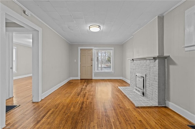 unfurnished living room featuring baseboards, wood finished floors, and crown molding