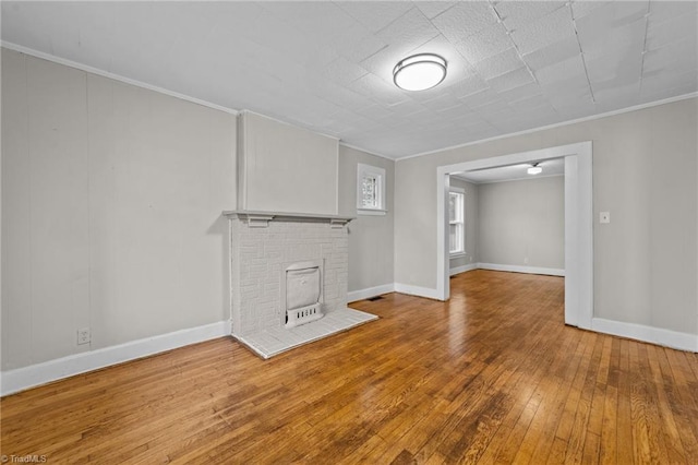 unfurnished living room featuring baseboards, ornamental molding, and hardwood / wood-style floors