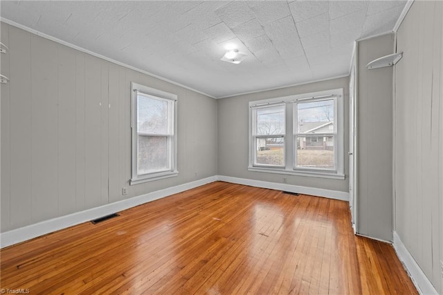 spare room with baseboards, light wood-style floors, and crown molding