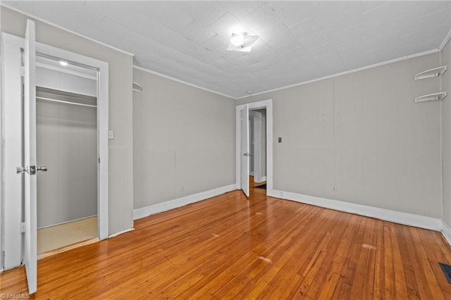 unfurnished bedroom with baseboards, hardwood / wood-style floors, visible vents, and crown molding