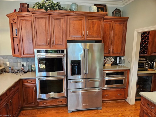 kitchen with backsplash, stainless steel appliances, wine cooler, hardwood / wood-style flooring, and ornamental molding