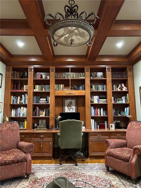 home office featuring coffered ceiling, built in shelves, light hardwood / wood-style floors, built in desk, and beam ceiling