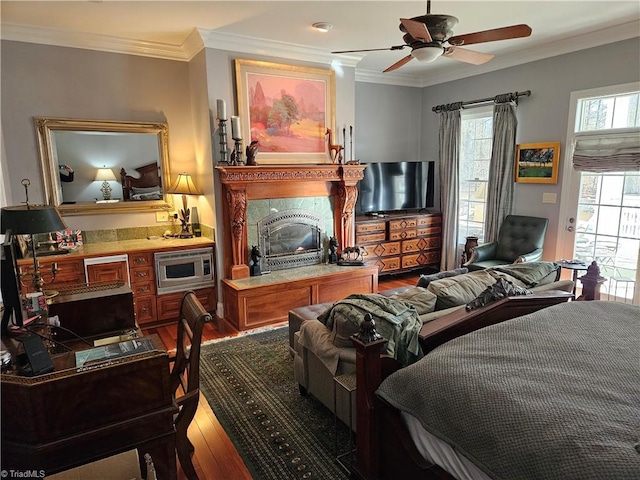 bedroom with ornamental molding, ceiling fan, dark hardwood / wood-style flooring, and a fireplace