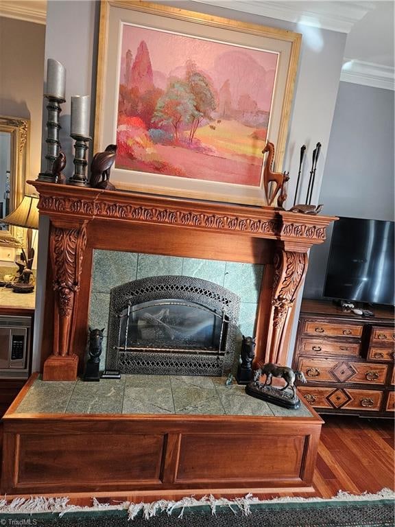 room details with ornamental molding, stainless steel microwave, hardwood / wood-style flooring, and a fireplace