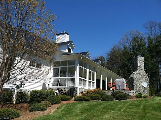 rear view of property with a sunroom and a yard