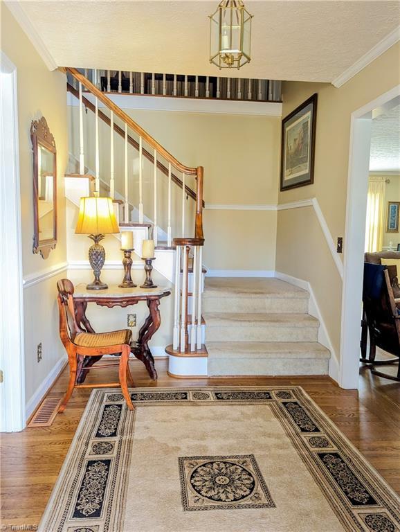 stairway featuring crown molding and hardwood / wood-style floors