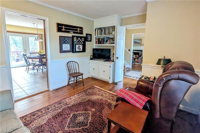 living room featuring light hardwood / wood-style flooring, french doors, and ornamental molding