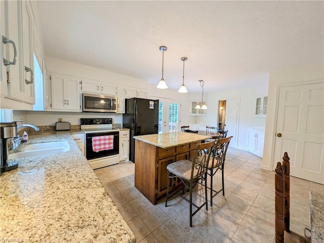 kitchen featuring sink, electric range, decorative light fixtures, white cabinets, and a center island