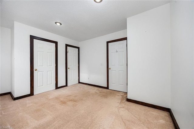 unfurnished bedroom featuring a textured ceiling and light carpet