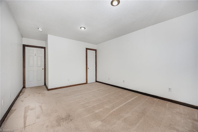 empty room with a textured ceiling and light carpet