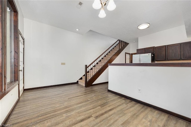 unfurnished living room featuring hardwood / wood-style flooring and a chandelier