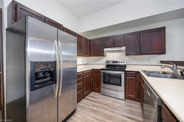 kitchen with stainless steel appliances, sink, and light hardwood / wood-style flooring