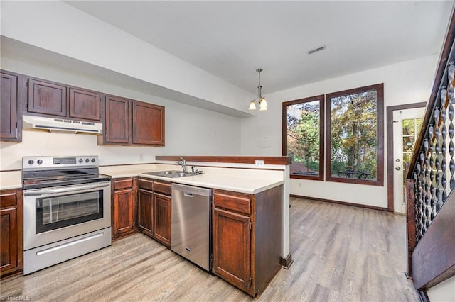 kitchen with stainless steel appliances, kitchen peninsula, hanging light fixtures, sink, and light hardwood / wood-style flooring