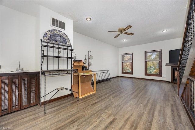 living room featuring hardwood / wood-style flooring, ceiling fan, a textured ceiling, and sink