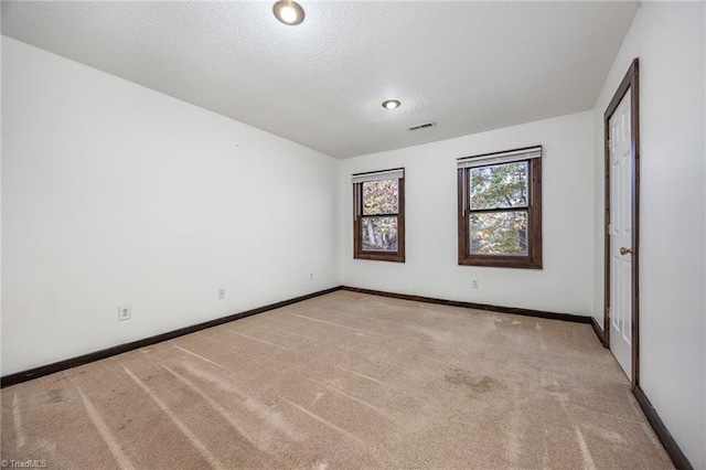 carpeted empty room featuring a textured ceiling