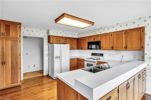 kitchen featuring kitchen peninsula, light wood-type flooring, white appliances, and sink