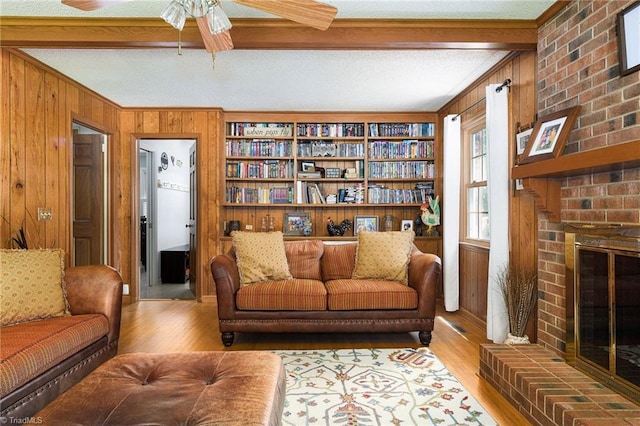 3600 Spicebush Trl, Greensboro, NC 27410 - living area with wooden walls, beamed ceiling, a fireplace, wood finished floors, and a ceiling fan