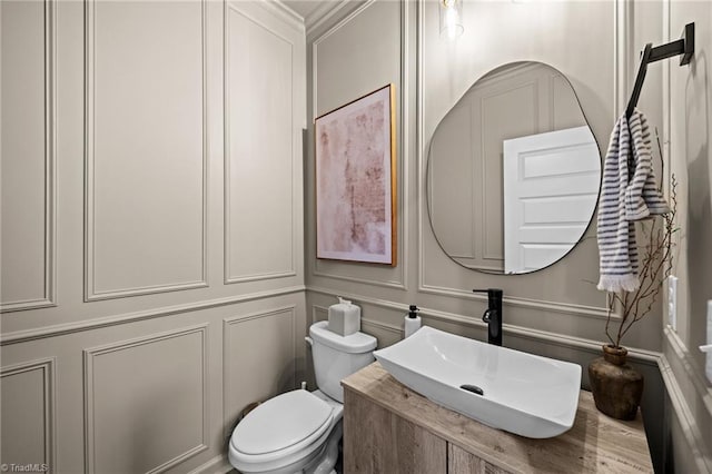 bathroom featuring vanity, a decorative wall, and toilet