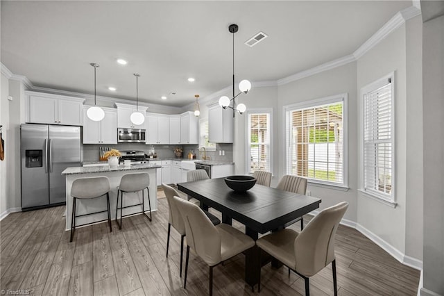 dining space featuring crown molding, recessed lighting, baseboards, wood finished floors, and visible vents
