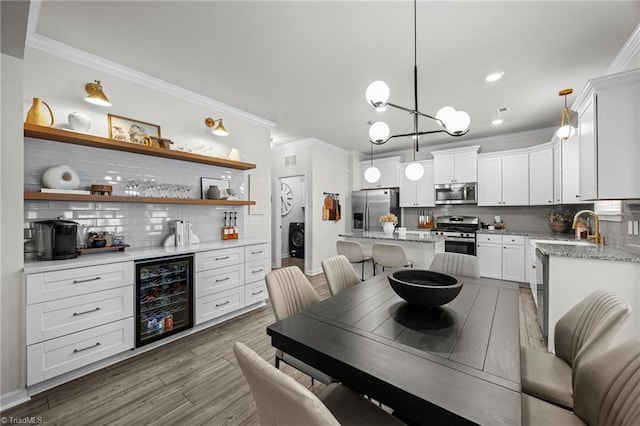 dining space with crown molding, washer / dryer, wine cooler, dark wood-style floors, and indoor bar