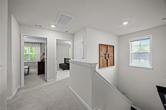 corridor featuring baseboards, visible vents, light carpet, and an upstairs landing