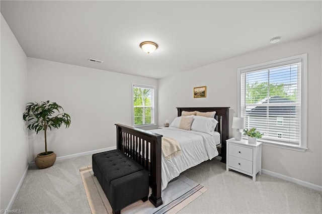 bedroom featuring visible vents, baseboards, and light carpet