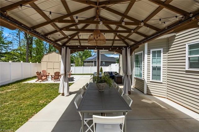 view of patio / terrace featuring a fenced backyard, an outdoor structure, a gazebo, and a shed