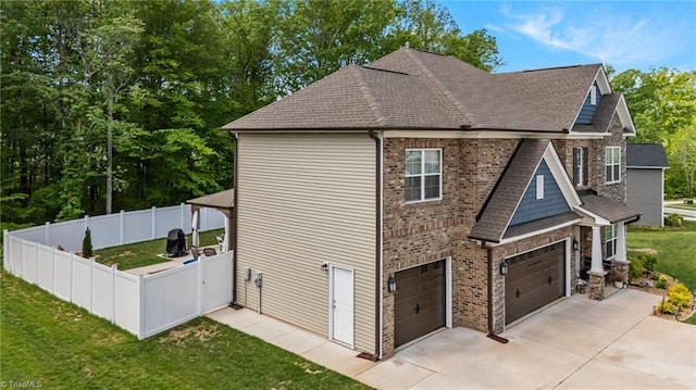view of side of home featuring a lawn, a gate, a garage, fence, and concrete driveway