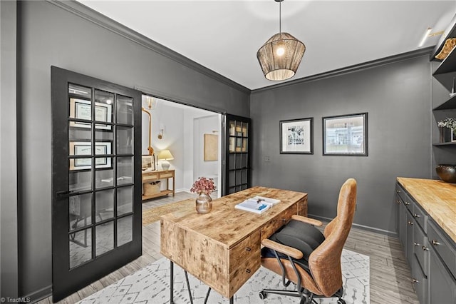 home office featuring light wood-type flooring, ornamental molding, and baseboards
