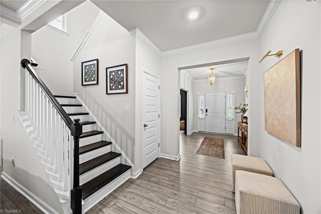 entrance foyer with crown molding, baseboards, wood finished floors, and stairway