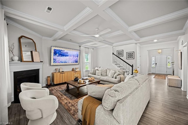 living room with a fireplace, stairs, beam ceiling, and wood finished floors