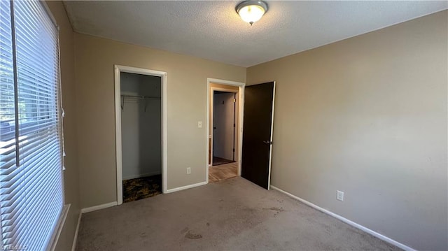 unfurnished bedroom featuring a textured ceiling, light colored carpet, and a closet