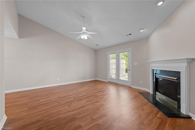 unfurnished living room featuring a glass covered fireplace, ceiling fan, vaulted ceiling, wood finished floors, and baseboards