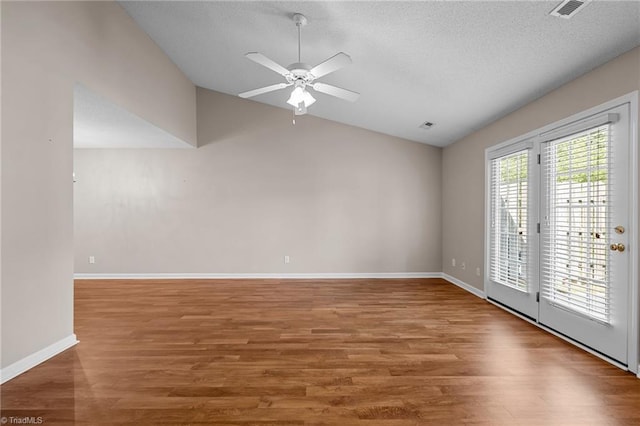 unfurnished room with visible vents, baseboards, lofted ceiling, ceiling fan, and wood finished floors