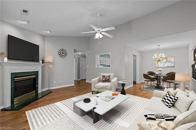 living room with a premium fireplace, wood finished floors, visible vents, and baseboards