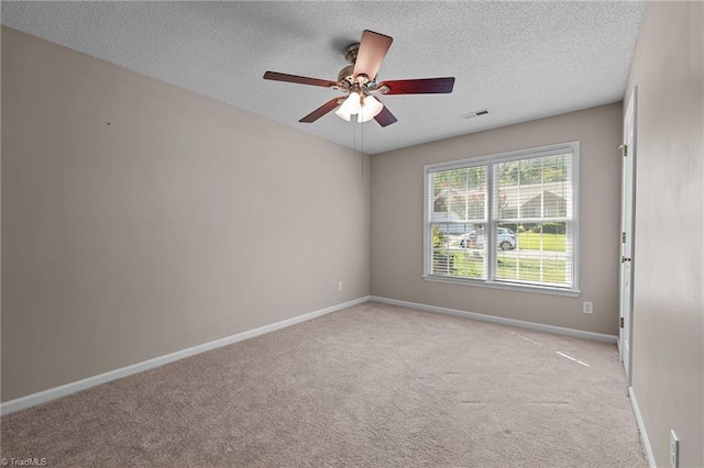 empty room with light colored carpet, visible vents, a ceiling fan, a textured ceiling, and baseboards