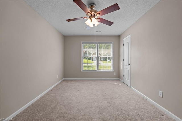 spare room featuring a textured ceiling, ceiling fan, light colored carpet, visible vents, and baseboards