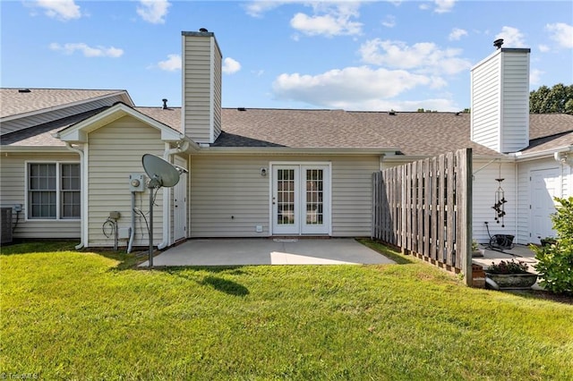 rear view of house featuring french doors, a chimney, a patio area, and a lawn