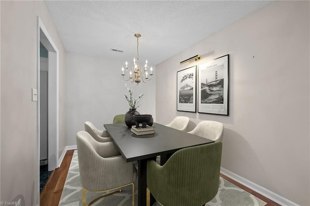 dining space featuring a textured ceiling, dark wood-type flooring, visible vents, and baseboards