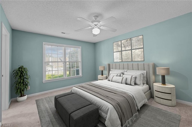 bedroom with visible vents, baseboards, light colored carpet, ceiling fan, and a textured ceiling