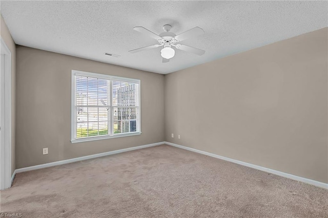 spare room with baseboards, ceiling fan, a textured ceiling, and light colored carpet