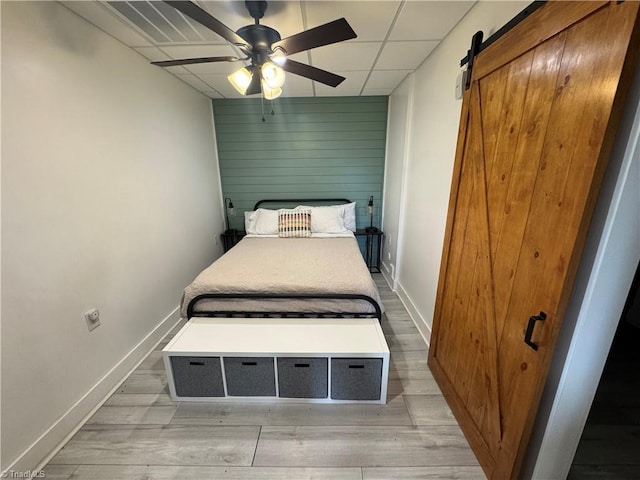 1346 Overland Trl, Hays, NC 28635 - bedroom featuring a barn door, light wood-style floors, baseboards, ceiling fan, and a paneled ceiling