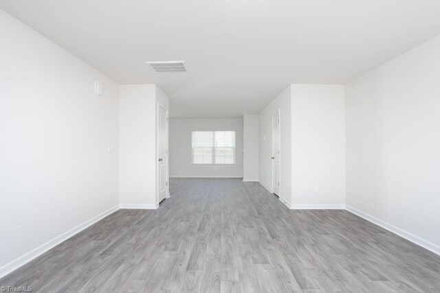 spare room with wood finished floors, visible vents, and baseboards