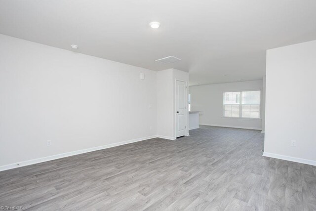 unfurnished living room with baseboards and wood finished floors