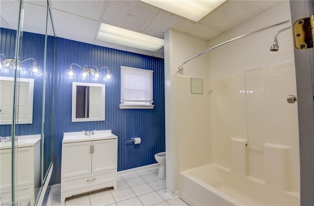 full bathroom with toilet, vanity, a drop ceiling, baseboards, and tile patterned floors