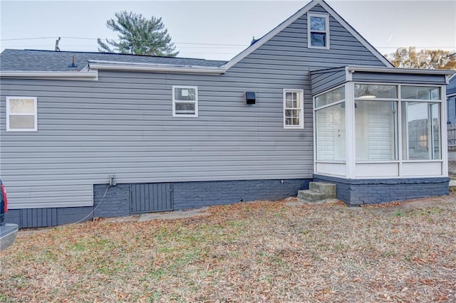 view of side of home with a sunroom and roof with shingles