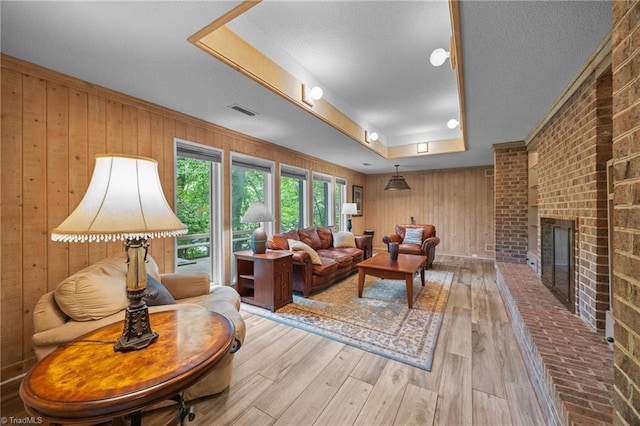3715 Bentbrook Dr, High Point, NC 27265 - living area featuring a raised ceiling, wooden walls, hardwood / wood-style floors, a brick fireplace, and a textured ceiling