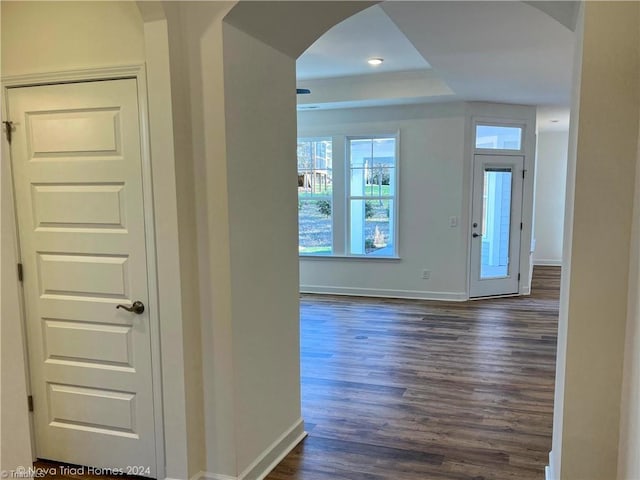 entryway with baseboards, arched walkways, and dark wood-type flooring