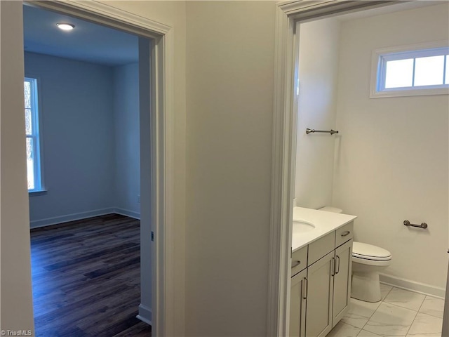 bathroom featuring toilet, vanity, and baseboards