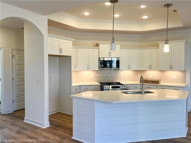 kitchen featuring stainless steel appliances, light countertops, white cabinetry, pendant lighting, and a sink